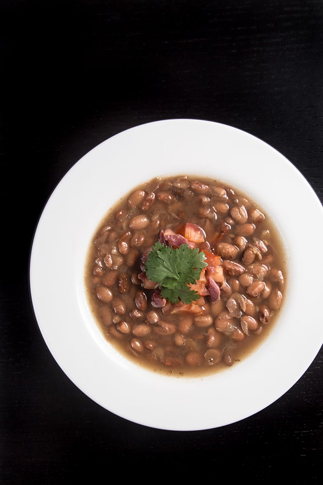 Overhead image of a white bowl of Smoky Ham Hock and Pinto Bean Soup made in an Instant Pot