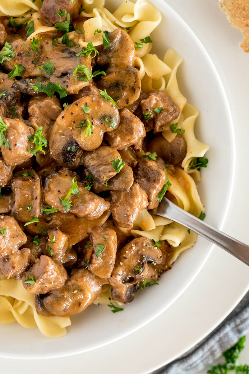 a vertical close-up shot showing the mushrooms and tender beef stroganoff served over egg noodles