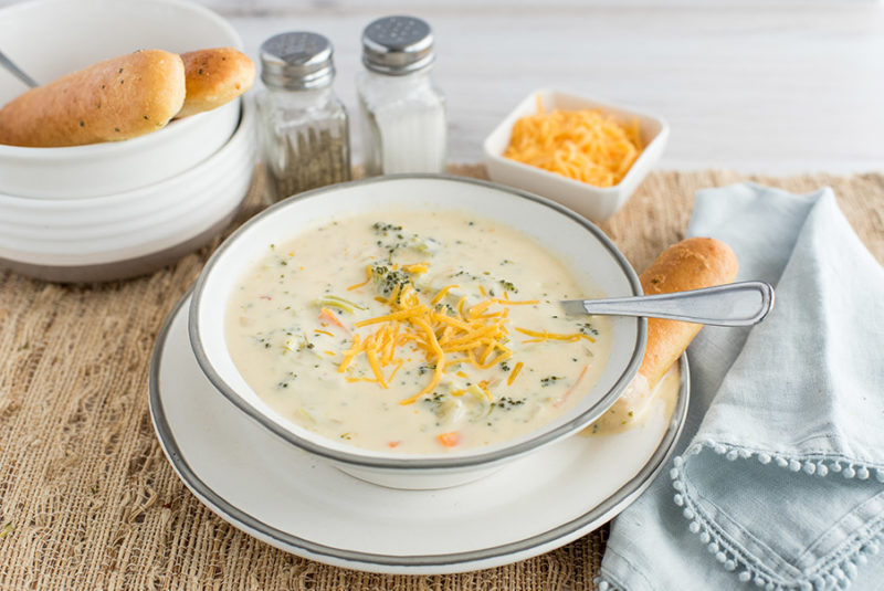 Pressure Cooker Broccoli Cheese Soup, dished up and ready to serve with additional shredded cheese and breadsticks