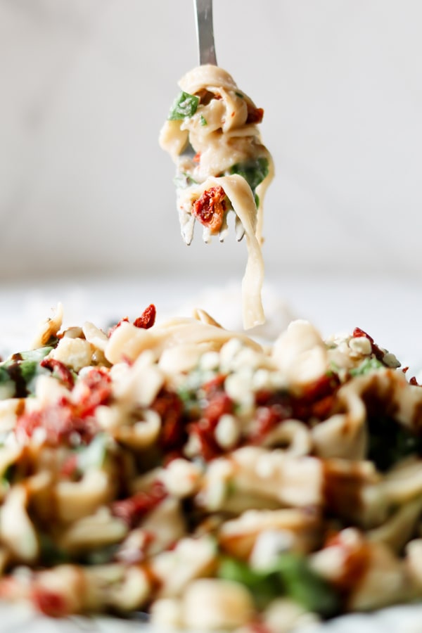 Pressure Cooker Cauliflower Fettuccine Alfredo spiraled onto a fork with a plate of it underneath the fork.