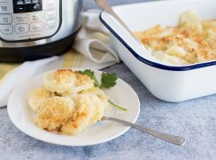 Instant Pot Scalloped Potatoes, plated on a small white plate with an Instant Pot Duo and a white baking dish in the background