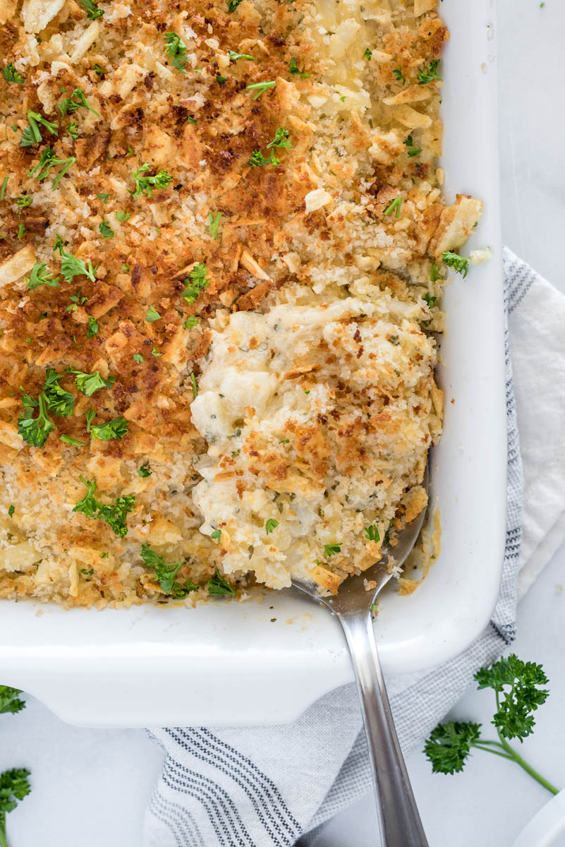 Overhead shot of Instant Pot hash brown casserole being scooped from a serving dish.