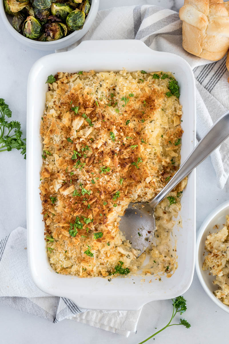 Overhead shot of a casserole dish with Instant Pot hash brown casserole served with browned topping with a serving spoon.