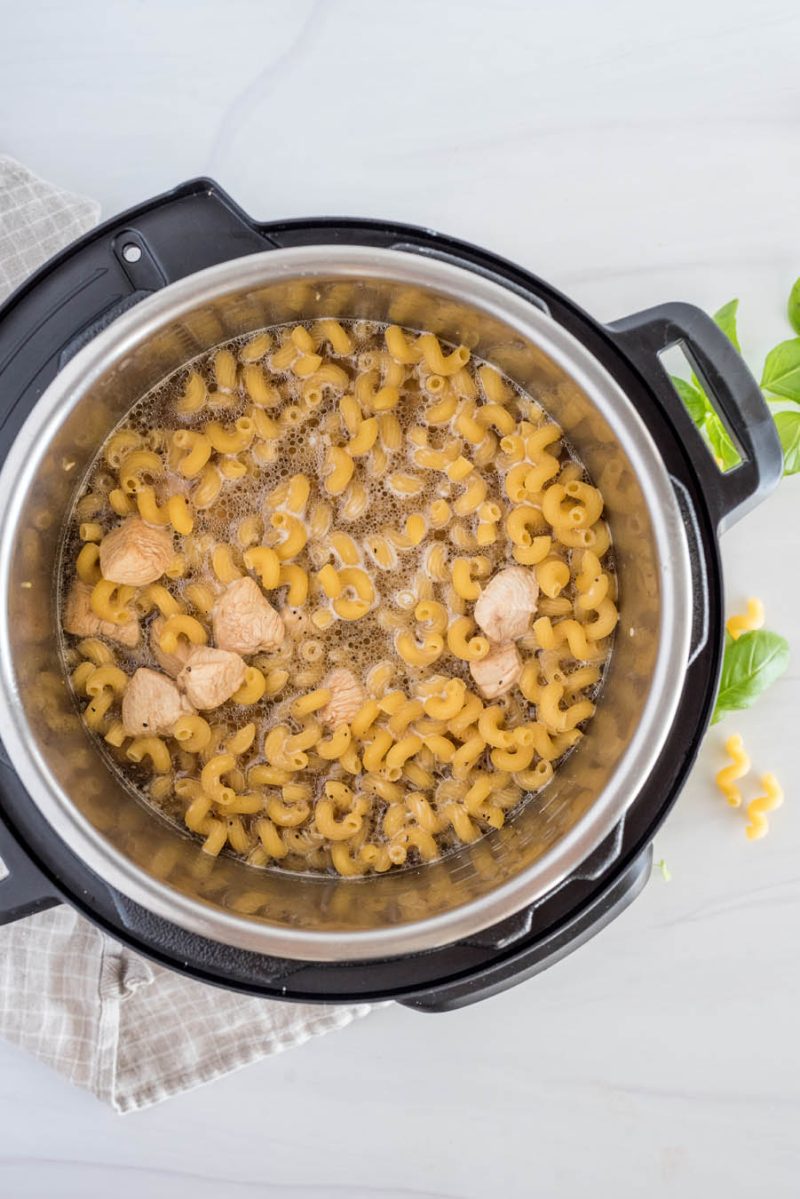 All the ingredients for chicken pesto pasta added to the Instant Pot and ready to cook.