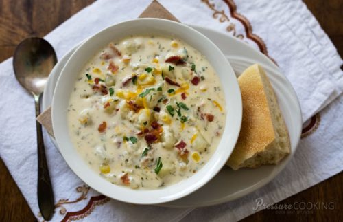 Potato Cheese Soup in a white bowl with bread on the side