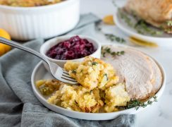 Instant Pot cornbread stuffing served on a plate with sliced turkey and cranberries with a fork.