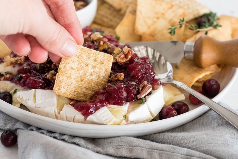 scooping baked brie with a cracker