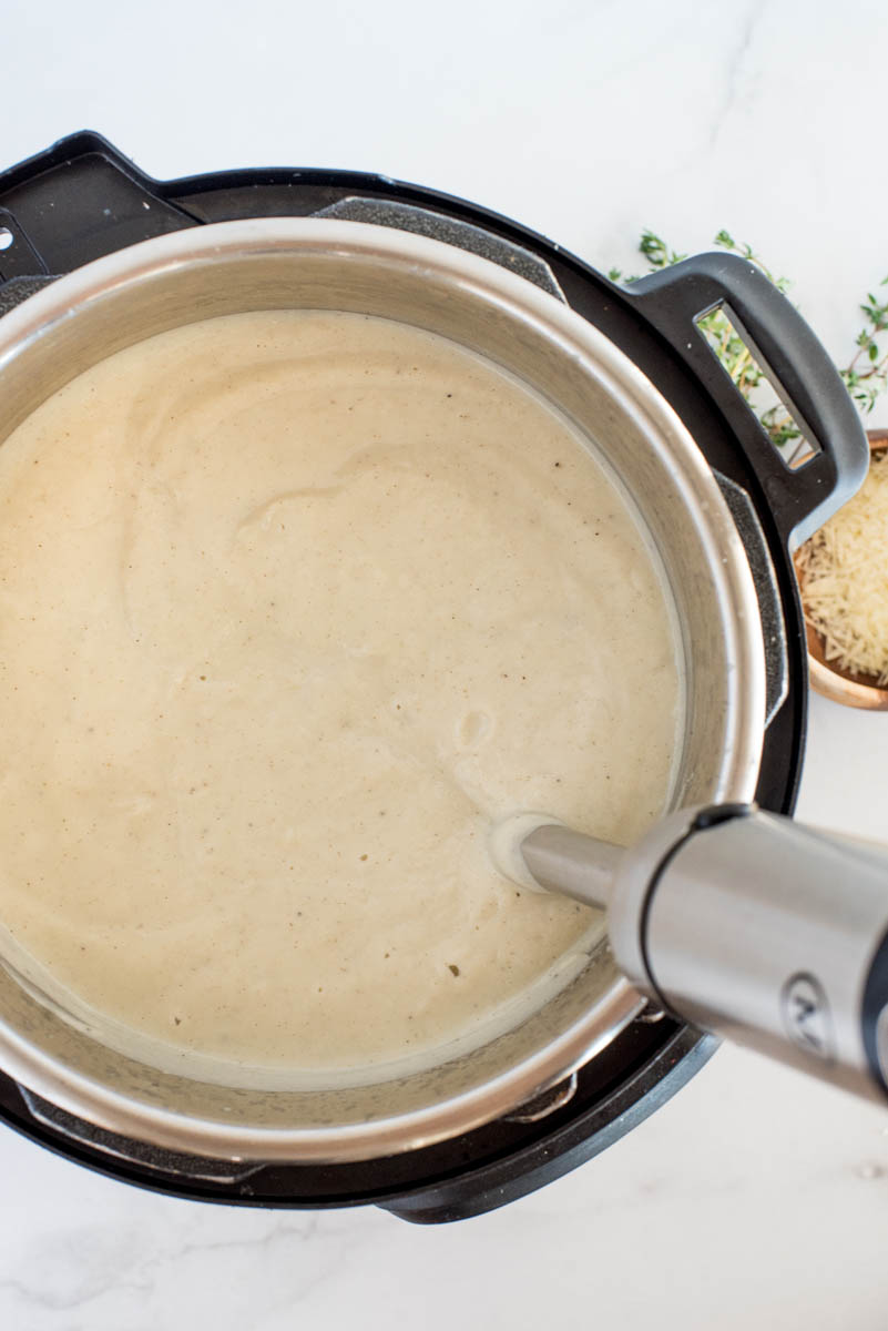 an overhead shot of using an immersion blender in an Instant Pot to mix the soup smoothly