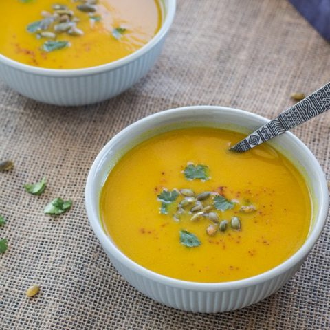 Pressure Cooker (Instant Pot) Curried Carrot Soup ready to eat in a white bowl with spoon in it.