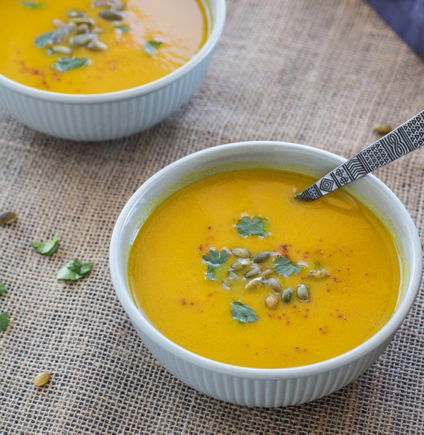 Pressure Cooker (Instant Pot) Curried Carrot Soup ready to eat in a white bowl with spoon in it.