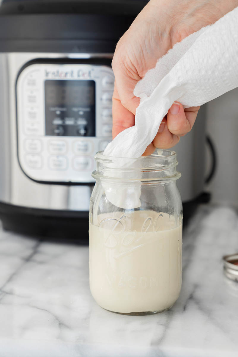 Cleaning up the edges of the mason jar with sweet and condense milk for making dulce de leche