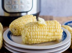 Easy Pressure Cooker Corn on the Cob, plated with an Instant Pot in the background