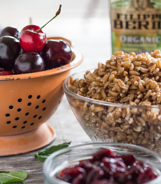 colander full of fresh cherries and a bowl of farro made in an Instapot to make Farro and Cherry Salad