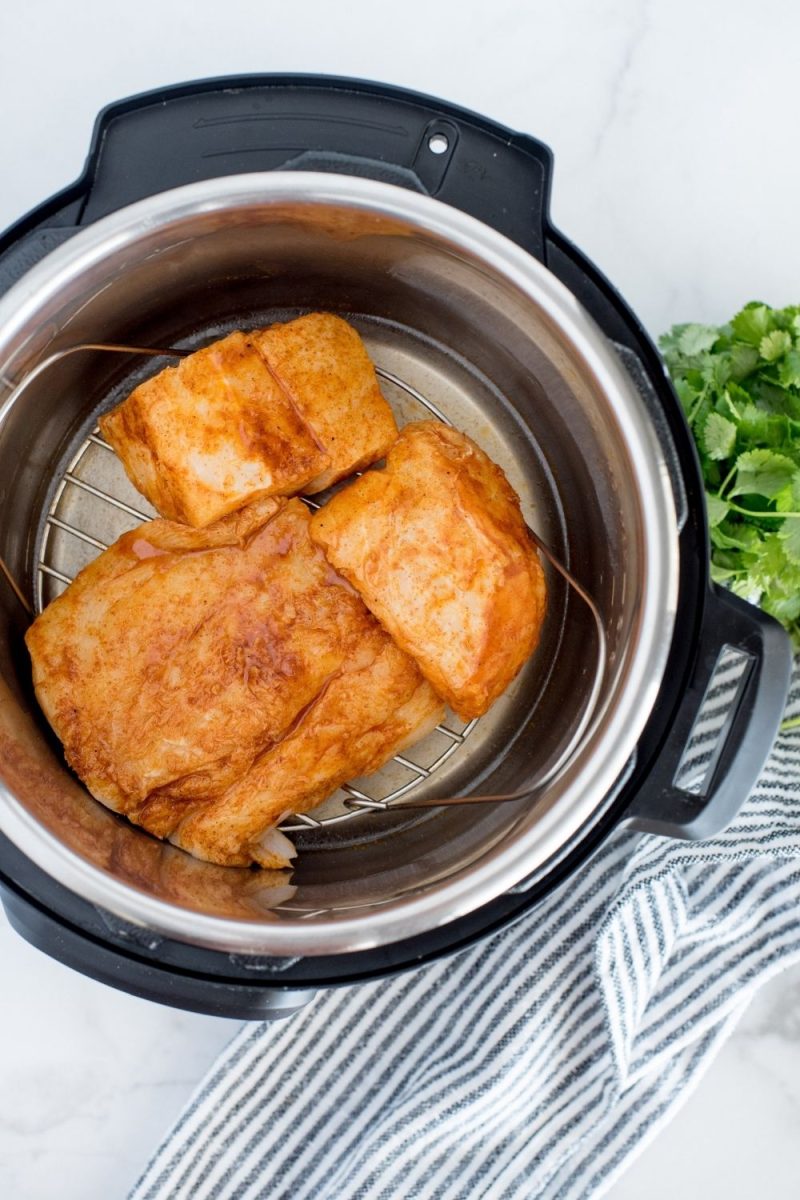An overhead shot looking into an instant pot filled with marinated fish before pressure cooking