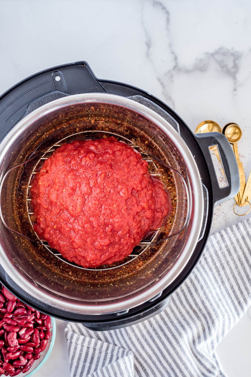 An overhead shot showing the tomatoes spread over the frozen ground beef in the chili