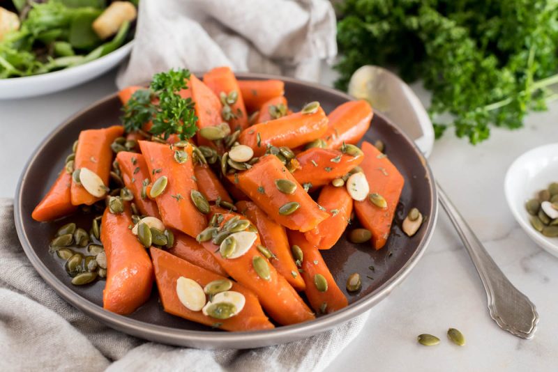 a 45 degree shot of Instant Pot glazed carrots, garnished with pepitas and pumpkin seeds and parsley