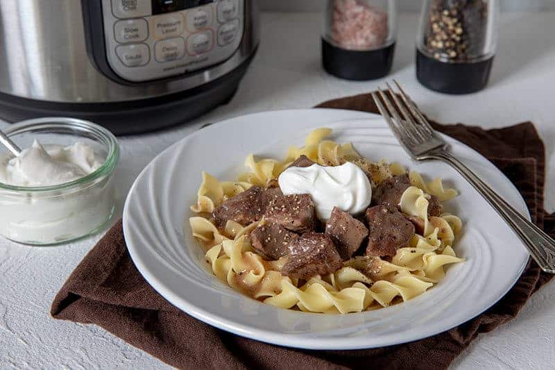 Sirloin-Tips-in-Gravy over noodles served on a white plate with a fork