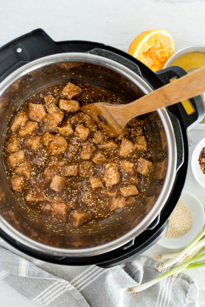 An overhead shot looking into an Instnat pot, after mixing the sauce and stirring in sesame seeds into the orange teriyaki chicken