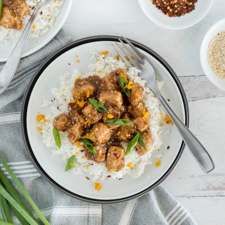 An overhead shot of Instant Pot Teriyaki Chicken, served with a fork and sesame seeds and red pepper flakes and green onions on the edges of the photo