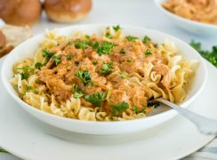 Close up picture of Instant Pot paprika chicken served over egg noodles with fresh parsley on top.