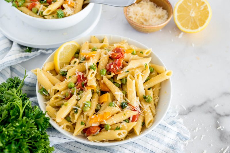 bowl of instant pot pasta primavera with fresh vegetables and parmesan cheese on top