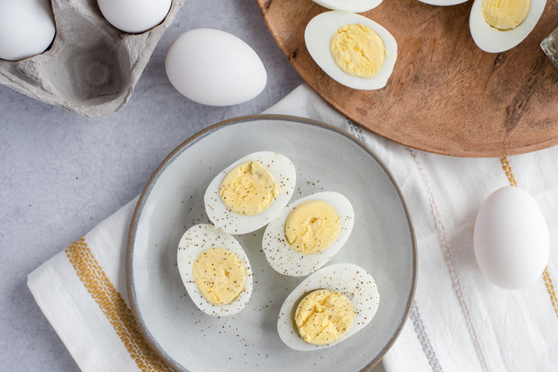 Overhead of a grey ceramic plate with four halves of perfectly cooked Instant Pot / pressure cooker hard-boiled eggs sprinkled with salt and black pepper