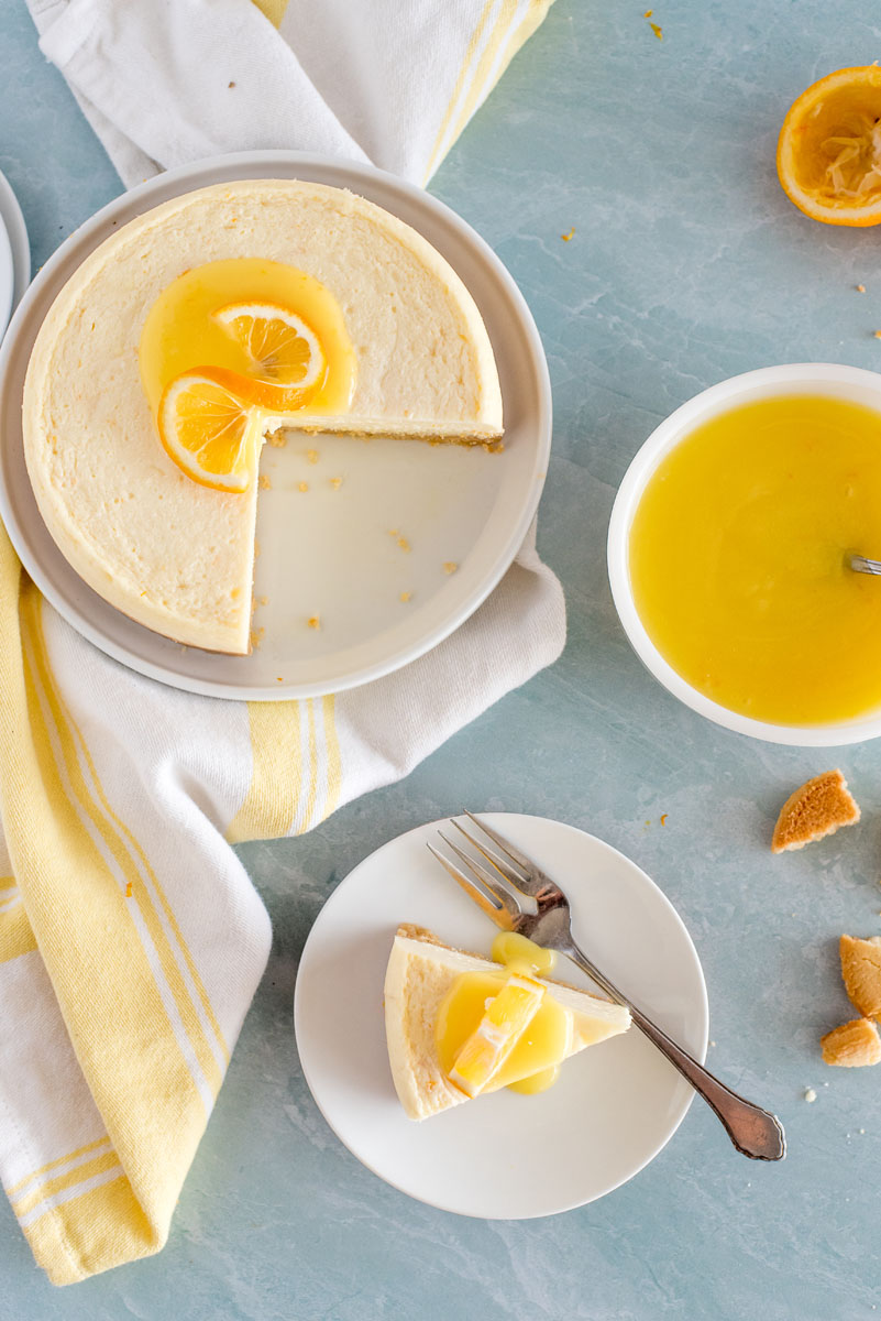 lemon cheesecake with slices removed on a blue bakcground