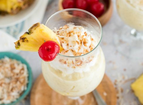 glass of coconut rice pudding with a pineapple and cherry on top