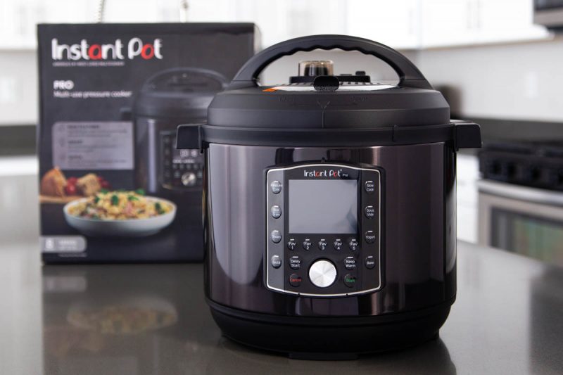 An Instant Pot Pro in black stainless steel sitting in front of the black Instant Pot box it came in