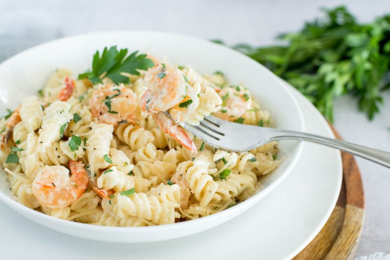 white bowl of instant pot shrimp alfredo rotini with parsley