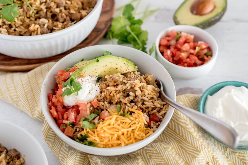 bowl of instnat pot taco rice with avocado, cheese, sour cream and tomatoes on top