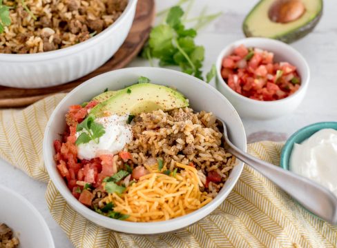 bowl of instnat pot taco rice with avocado, cheese, sour cream and tomatoes on top