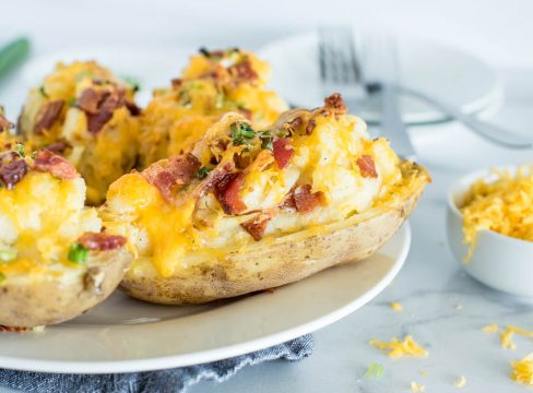 twice baked ranch potatoes on a white plate with bacon on top