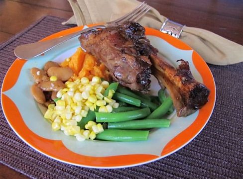 Pressure Cooker (Instant Pot) Luscious Lamb Shanks on a decorative plate with vegetables like green beans and corn on the side