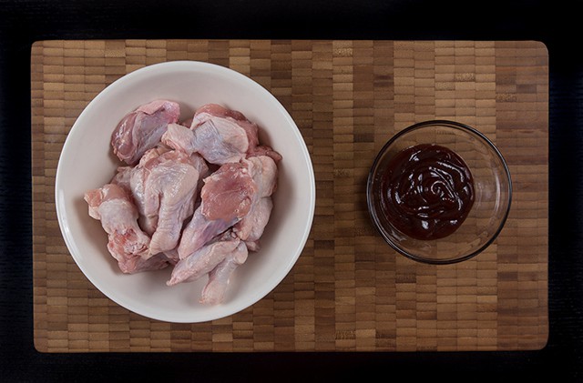 raw chicken wings and a glass prep cup of bbq sauce