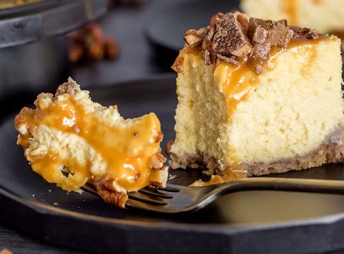 A fork taking a bite off of a piece of New York cheesecake that was made in an Instant Pot and topped with caramel and chocolate