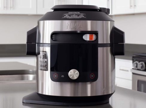 A direct head-on shot of the Ninja Foodi Smart XL Pressure COoker with SmartLid and Thermometer (model O701) sitting on a gray stone countertop with white cabinets in the background