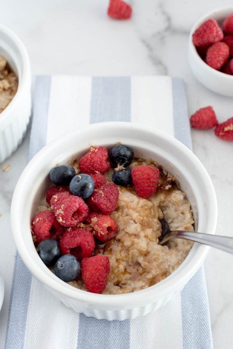 Overhead shot of Instant Pot oatmeal for one in a white bowl topped with brown sugar, raspberries, and blueberries.