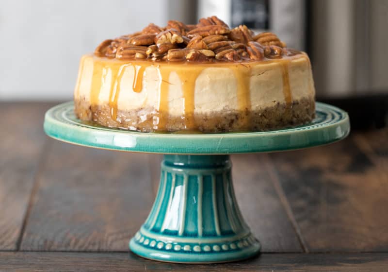 Pressure Cooker Caramel Pecan Cheesecake on an aqua colored cake stand