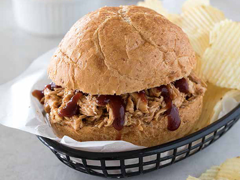 Shredded BBQ chicken sandwich on a bun served in a brown basket