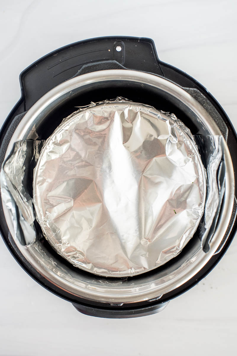 overhead of instant pot with a foil wrapped cheesecake pan
