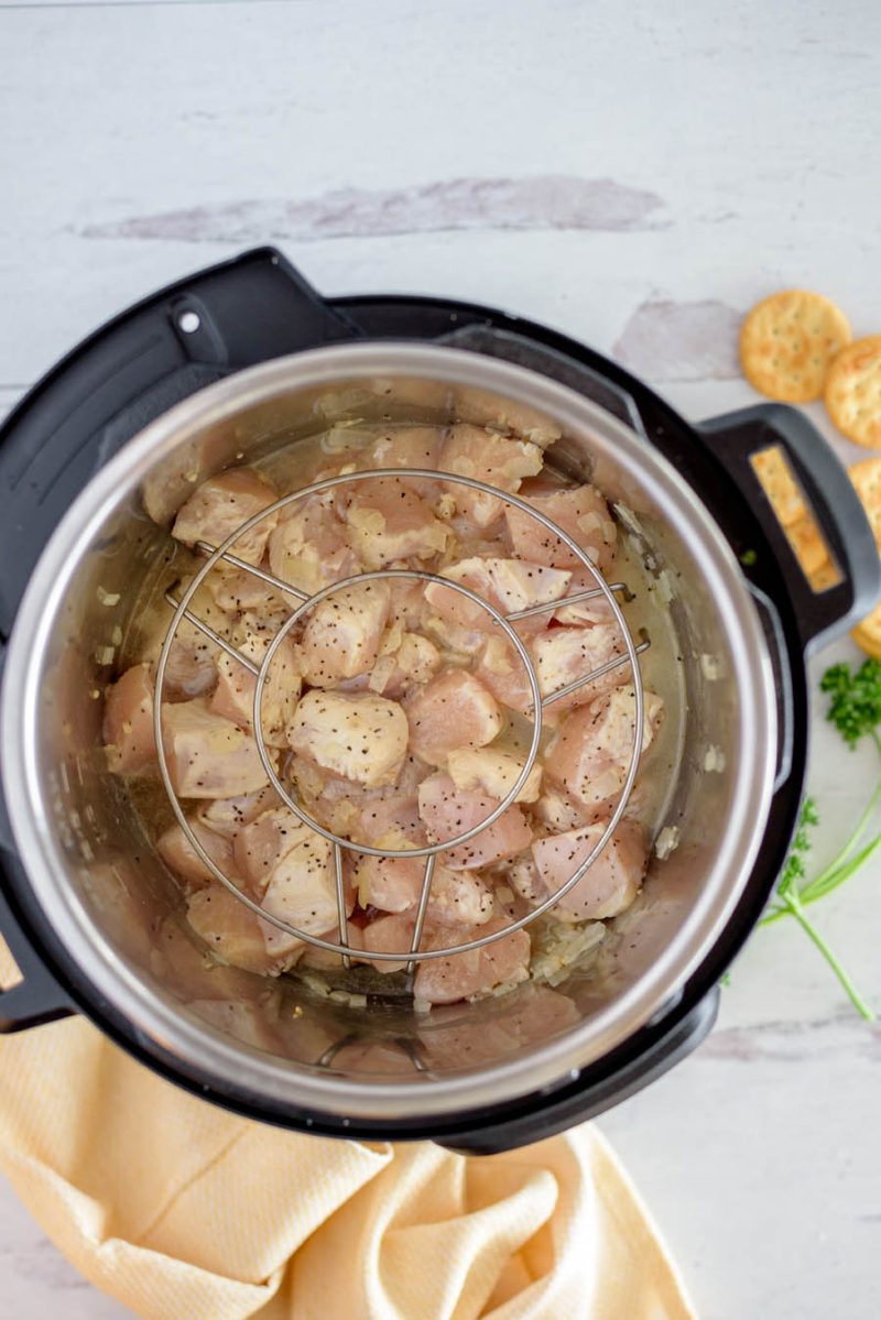 an overhead shot of the chicken in the pot, with a trivet ready to lower the rice on