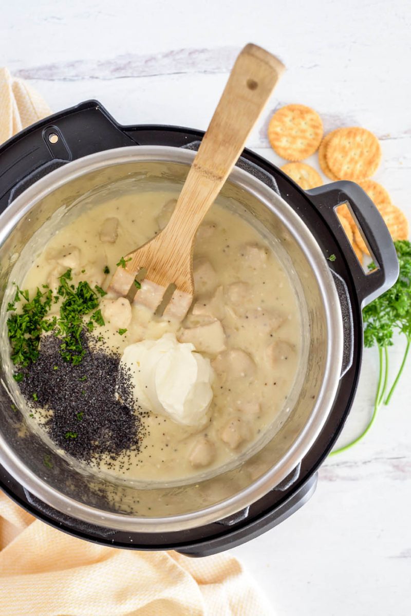 An overhead shot of the parsley, cream cheese, and poppy seeds in the creamy chicken sauce