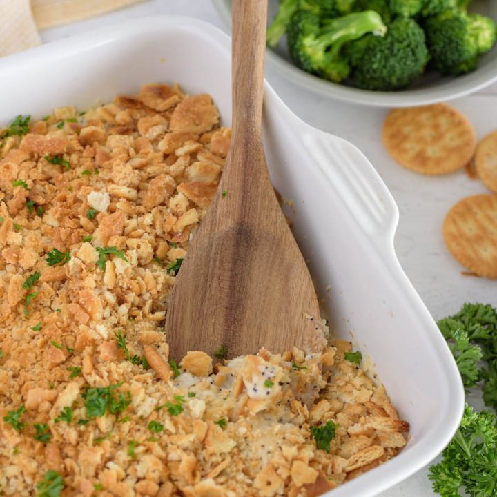 A close-up of a wooden spoon ready to scoop out a generous helping of chicken poppyseed casserole, made in the Instant Pot