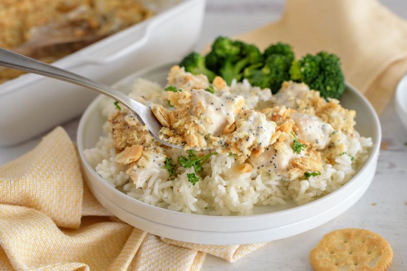 a side shot of a spoonful of poppyseed chicken casserole made in the Instant Pot served with steamed broccoli