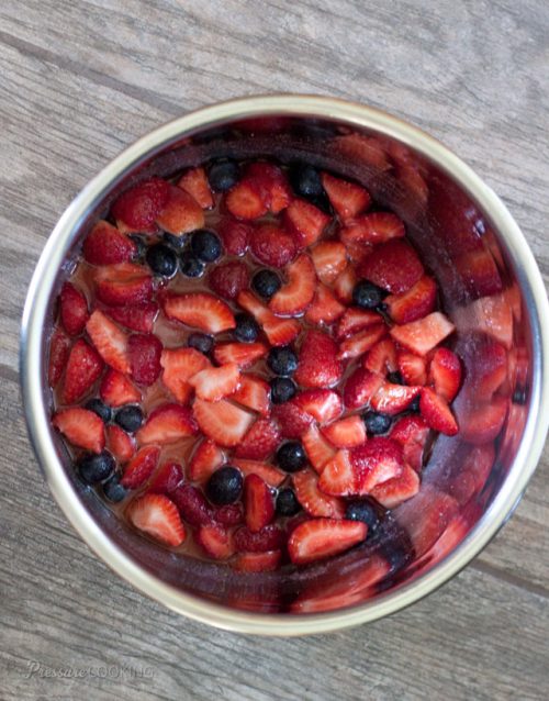 overhead shot of an Instant Pot cooking pot filled with diced fresh strawberries and blueberries, ready to go into the pressure cooker.