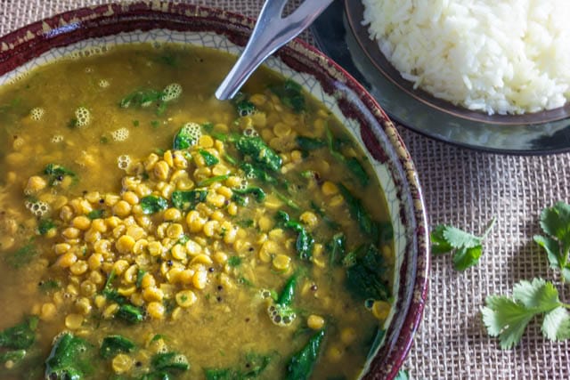 glazed pottery soup bowl filled with Pressure Cooker Dal With Spinach next to a dish of fluffy white rice