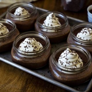 half pint jars filled with Pots de Crème made in an electric pressure cooker, topped with whipped cream and chocolate jimmies