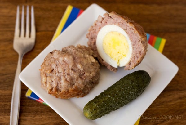 Pressure Cooker (Instant Pot) Scotch Eggs on a white plate with a pickle