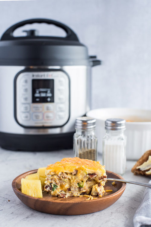 A slice of Pressure Cooker Meat Lovers Crustless Quiche, plated with an Instant Pot in the background